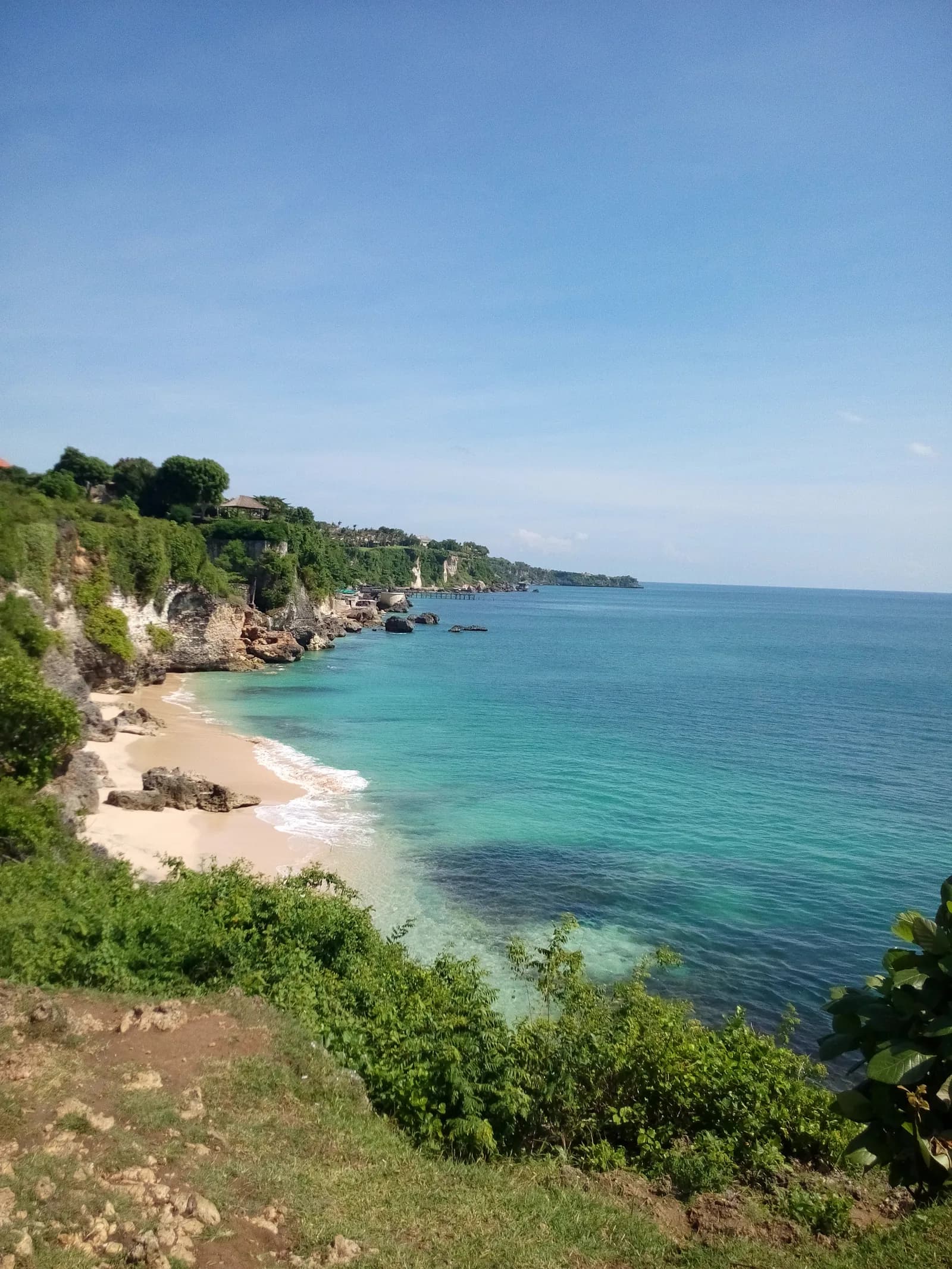 The Bukit coastline near Padang Padang seen from the clifftop, a small beach and turquoise reef below, Bali