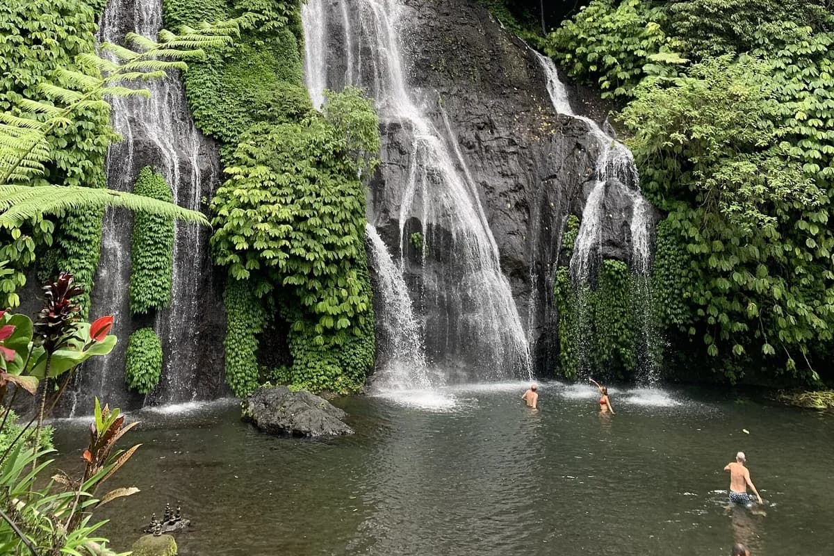 Swimmers wading in the natural pool at the foot of Banyumala Waterfall, Wanagiri, Buleleng, north Bali