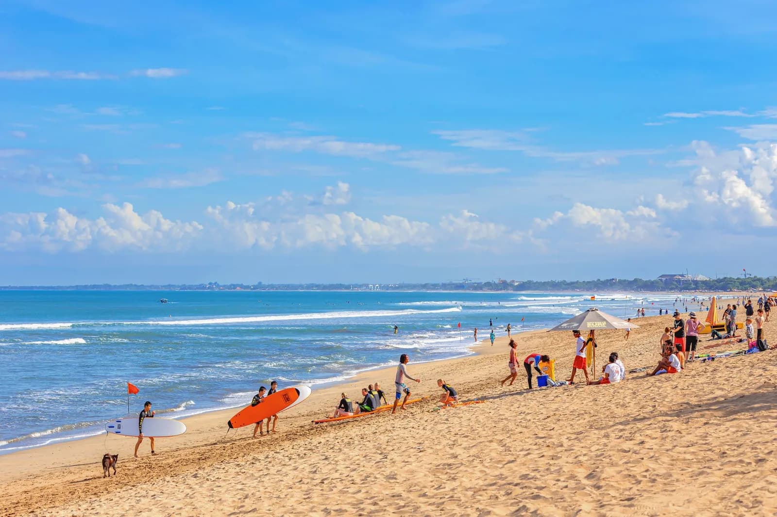 Surf instructors and beginners with soft-top boards on the sand at Kuta Beach, Bali
