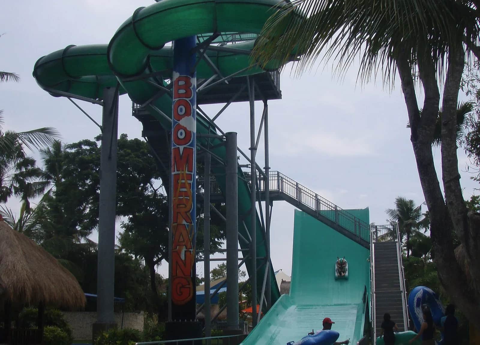 The Boomerang slide tower and its green spiral among palm trees at Waterbom Bali, Kuta