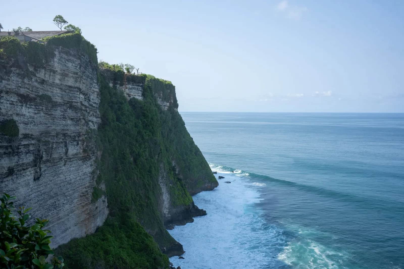 Lines of south swell wrapping into the limestone cliffs at Uluwatu under a clear September sky, Bali