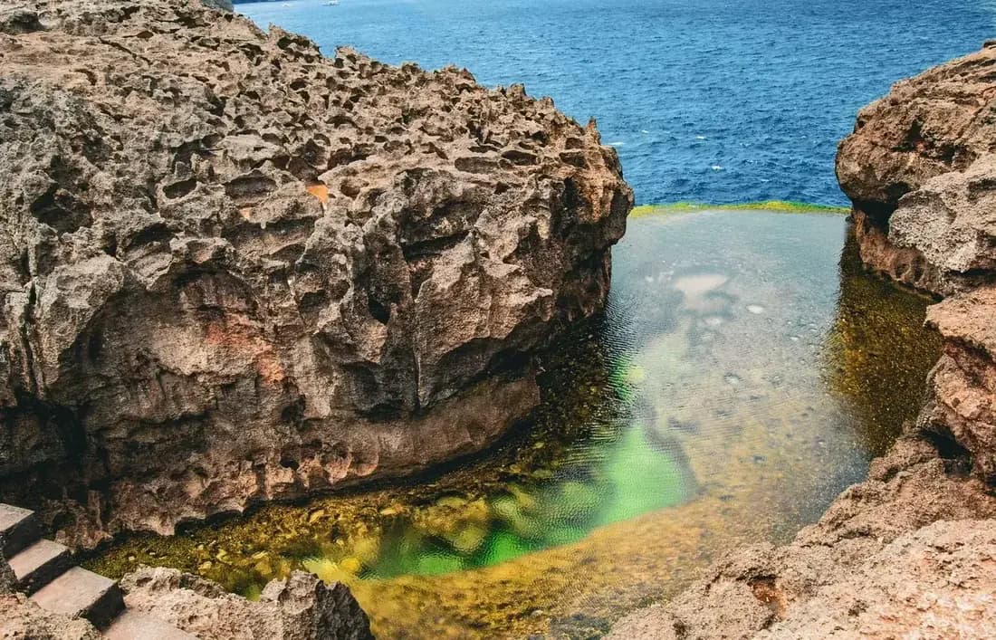 Angel's Billabong tidal rock pool with clear green water over pale rock, opening onto the open sea