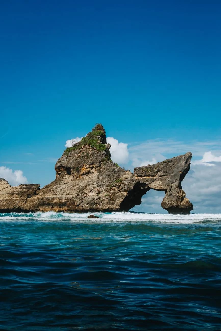 The pierced rock arch standing in the surf off Atuh Beach, Nusa Penida
