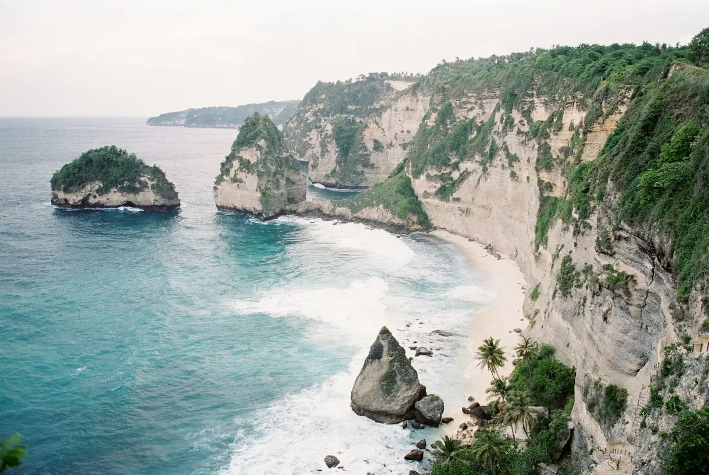 Cliffs, sea stacks and the white sand of Atuh Beach on the east coast of Nusa Penida