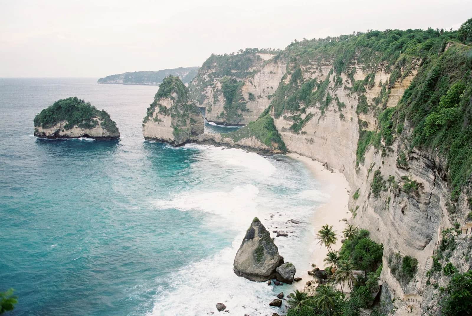 The Diamond Beach cove under its white limestone cliff with the Thousand Islands stacks offshore, Nusa Penida