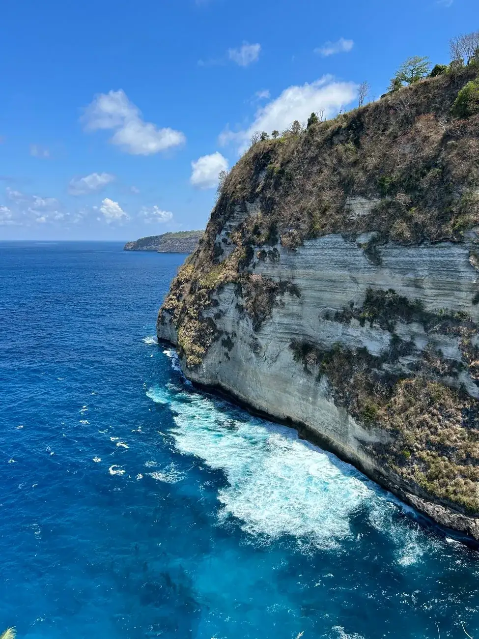 Deep blue water breaking against a limestone headland on the south coast of Nusa Penida