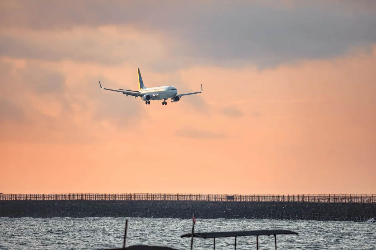 Aircraft on final approach over the sea to Ngurah Rai airport at sunset, Bali