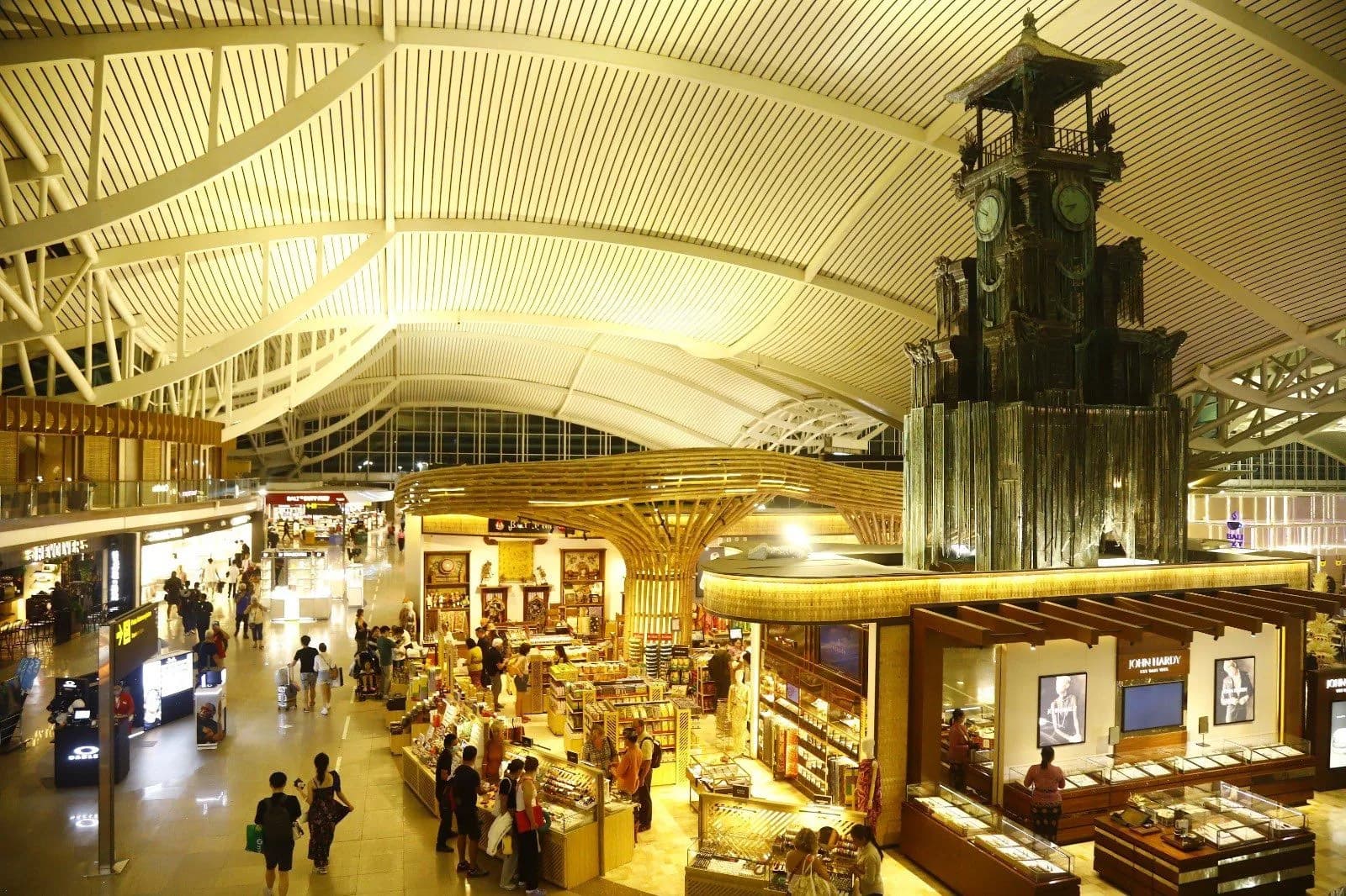 Duty free shops and restaurants around a carved wooden clock tower in the airside departure hall of Ngurah Rai airport, Bali