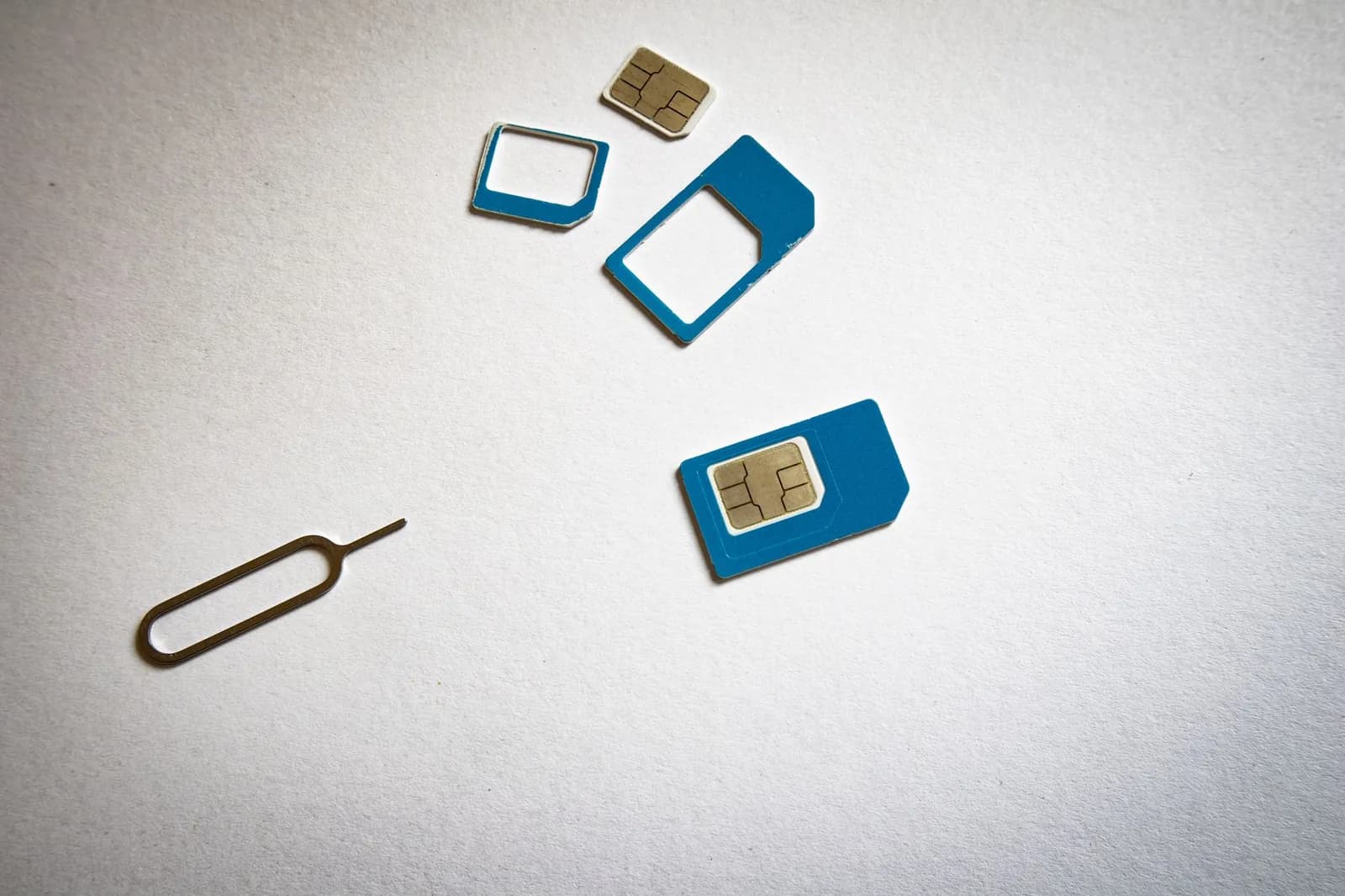 SIM cards in several sizes with a SIM ejector pin on a white background