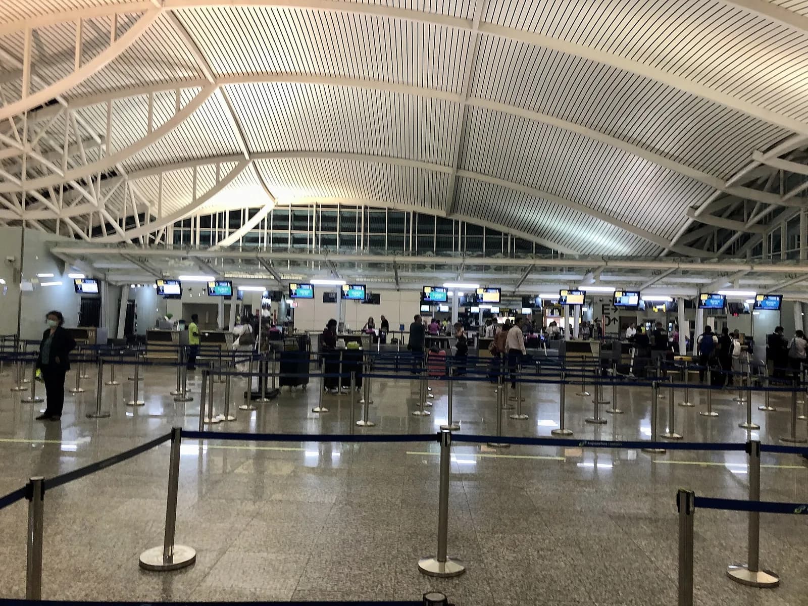 Queue lanes and counters under the curved white roof of the international terminal at Ngurah Rai airport, Bali