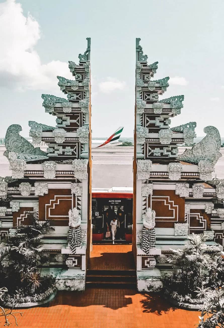 Traditional Balinese split gate at the airport terminal in Bali with an aircraft on the apron behind it