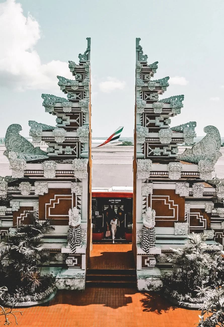 Traditional Balinese split gate at the airport terminal in Bali with an aircraft on the apron behind it