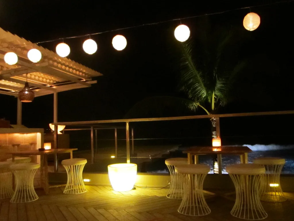 Upstairs bar terrace at Ku De Ta in Seminyak, Bali, with paper lanterns and white wire stools lit at night