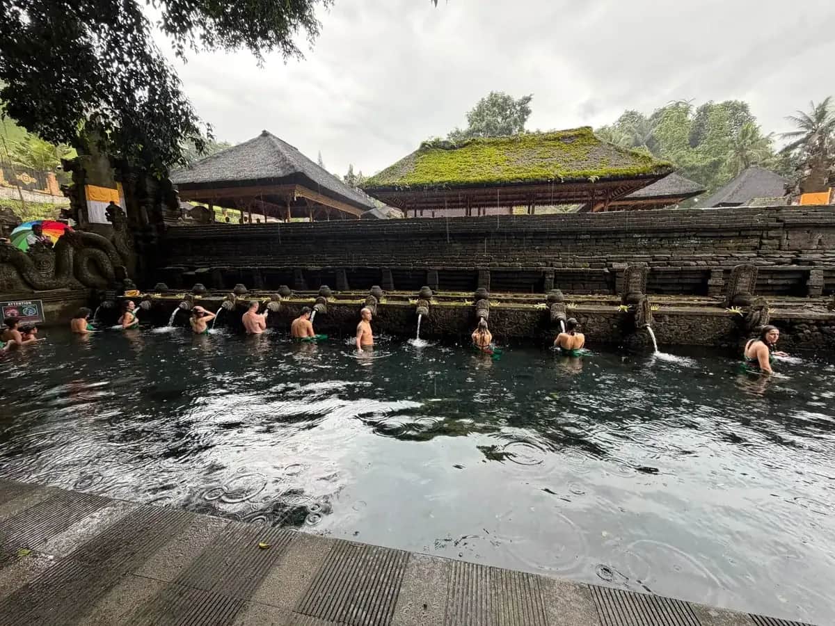 Visitors queueing along the row of stone spouts in the purification pool at Tirta Empul, Bali