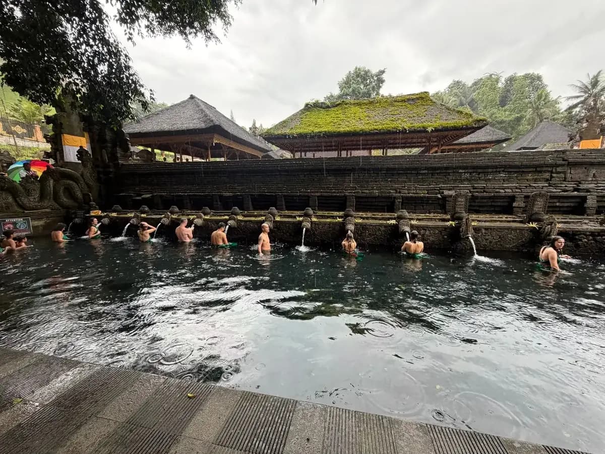 Visitors queueing along the row of stone spouts in the purification pool at Tirta Empul, Bali
