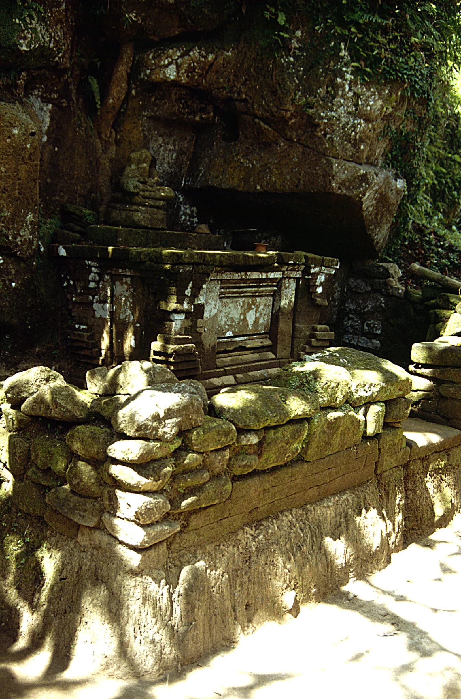 Weathered stone remains under an overhanging rock face in the ravine below Goa Gajah, Bedulu, Bali