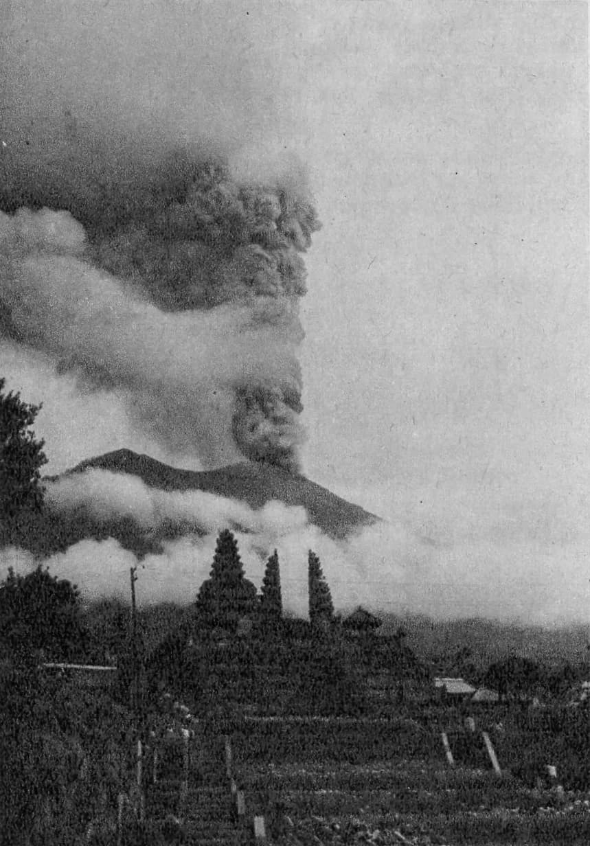 Archive photograph of the 1963 eruption column rising from Mount Agung above the meru towers of Besakih
