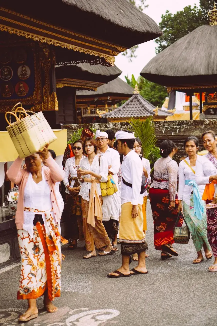 Balinese families in ceremonial dress carrying offerings into a village temple