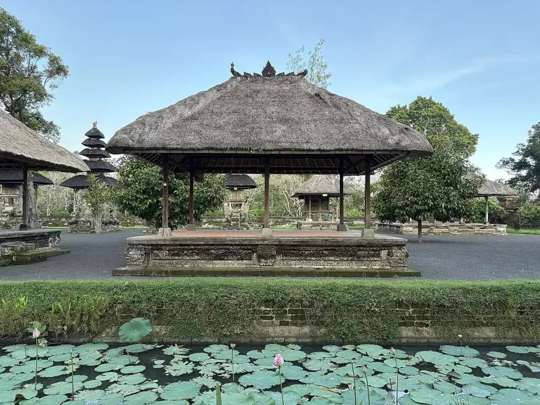 Open thatched pavilion at Taman Ayun behind a moat covered in water lilies