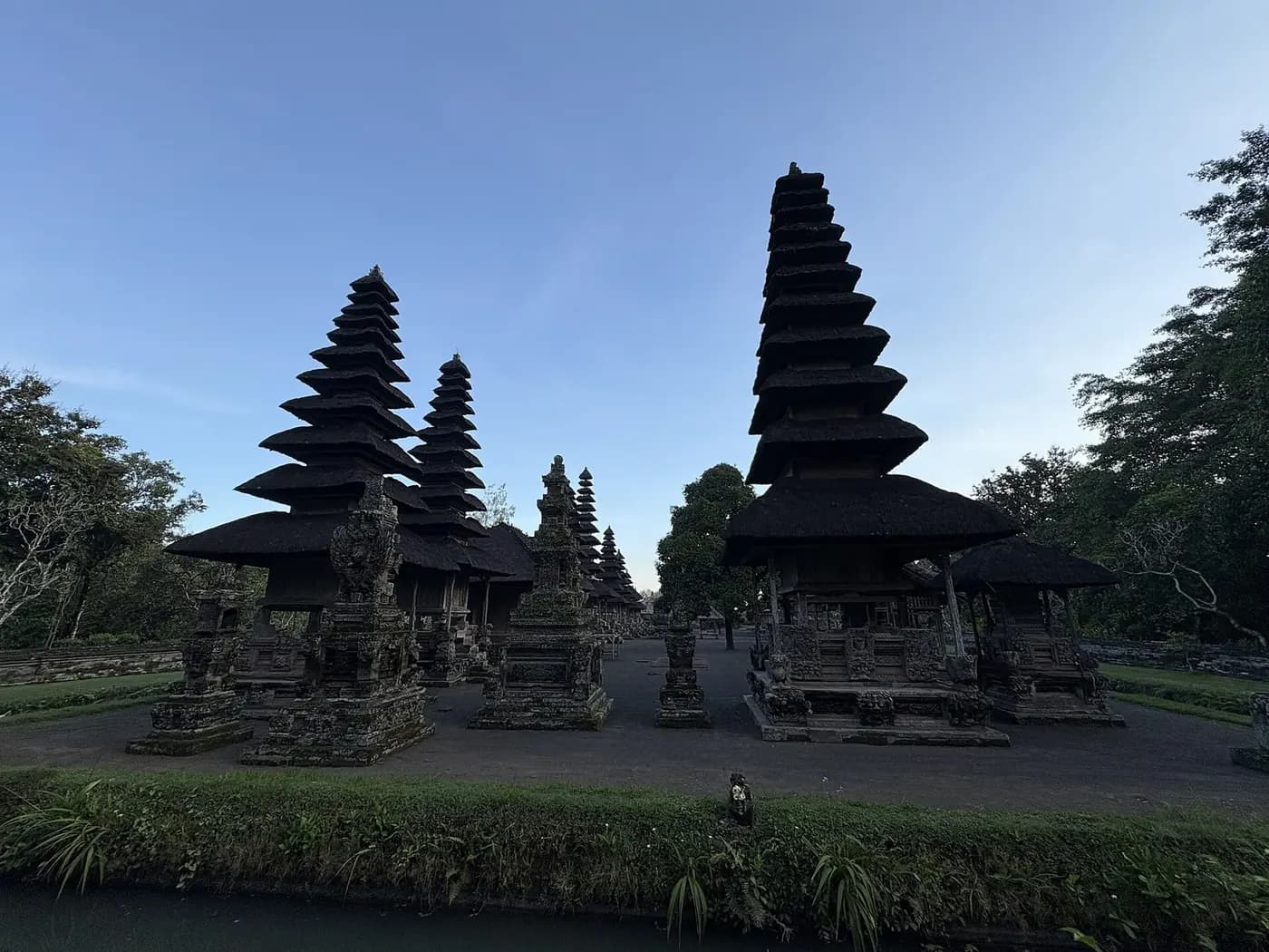 The inner courtyard of Taman Ayun with its row of meru towers, seen from the raised path outside the wall