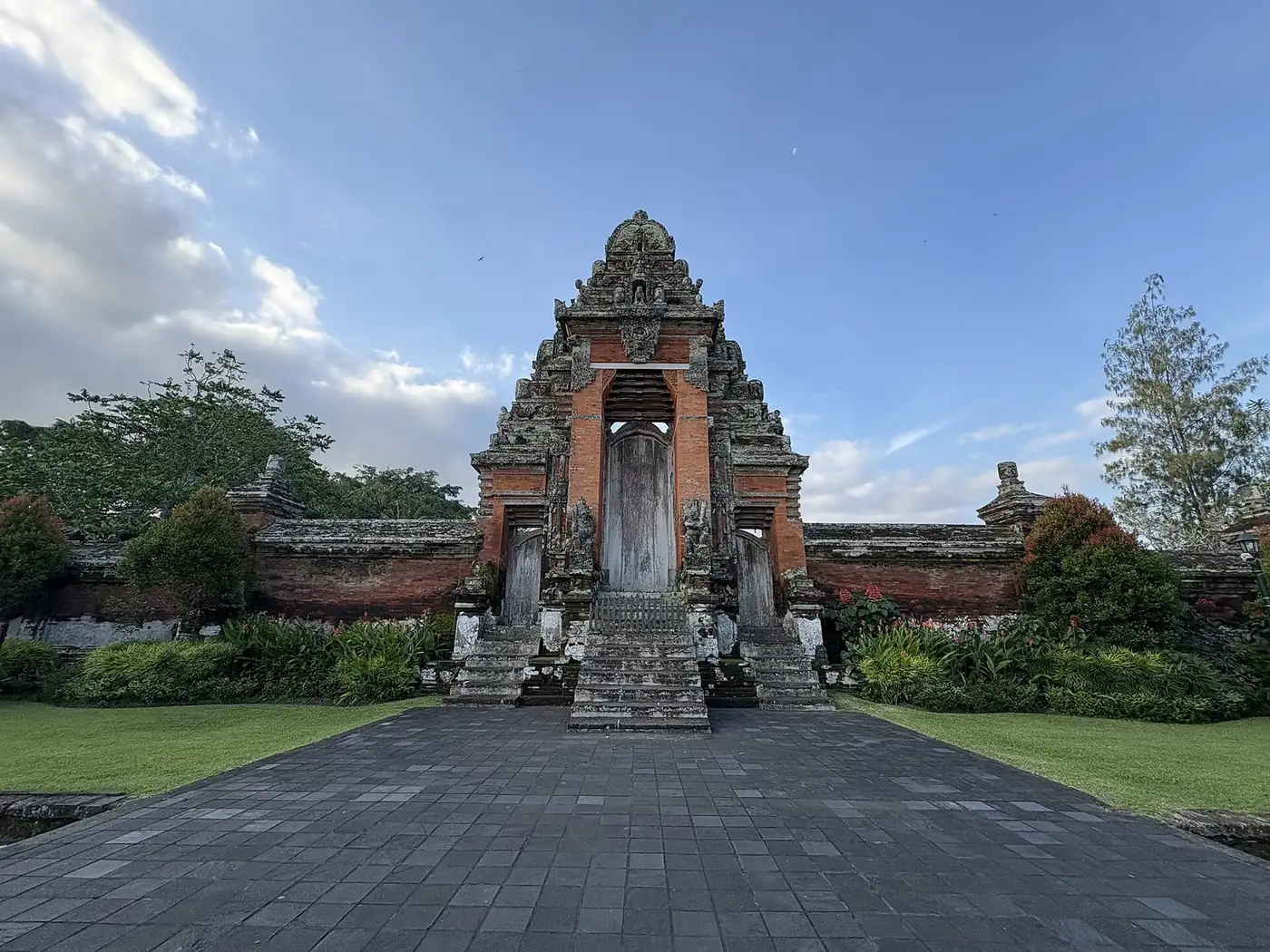 The tall roofed kori agung gate at Taman Ayun at the end of a paved causeway, closed to visitors