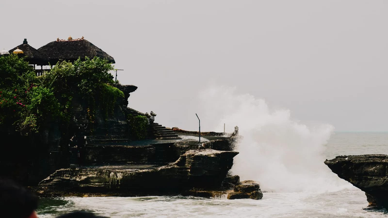 Surf breaking over the rock platform below Tanah Lot temple at high tide, closing the crossing, Bali