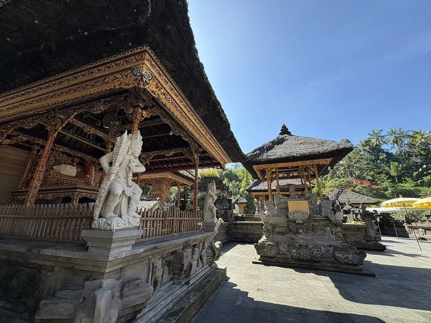 Gilded carved pavilion and stone guardian statues in the inner courtyard of Tirta Empul temple