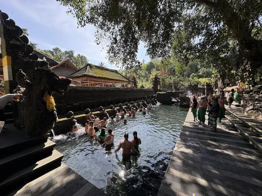 Bathers in sarongs working along the spouts of the second purification pool at Tirta Empul