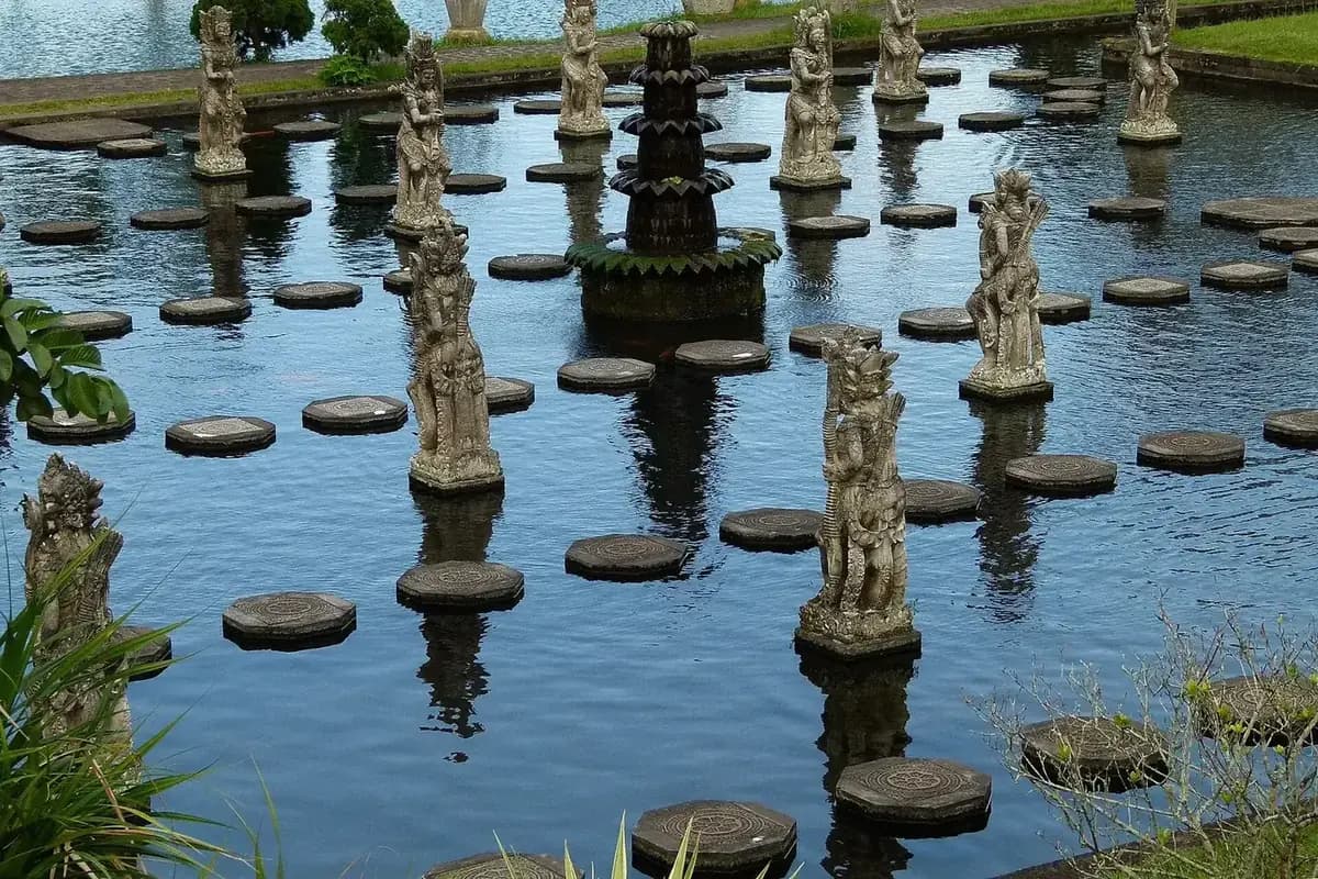 Round stone stepping stones and carved statues crossing the koi pond at Tirta Gangga, east Bali