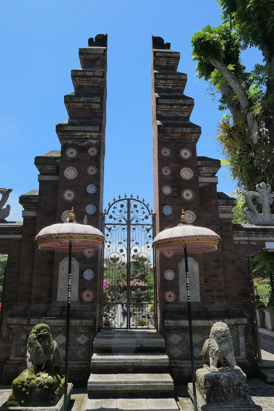 The brick split gate at the entrance to Tirta Gangga, with ceremonial parasols and stone lions