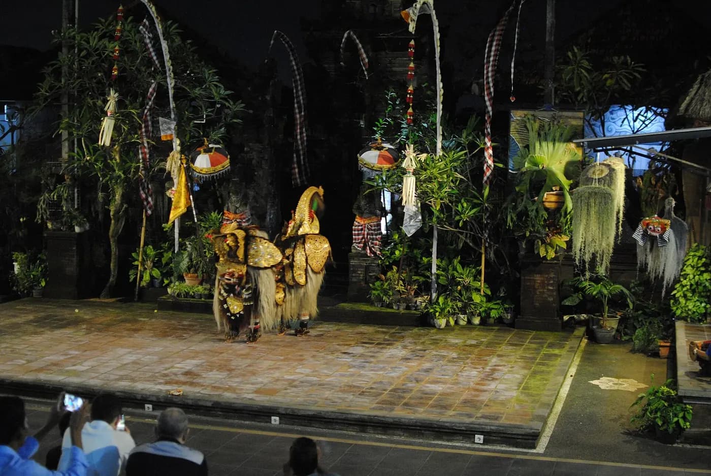 The barong creature in gold and shaggy white costume on a decorated Balinese stage at night