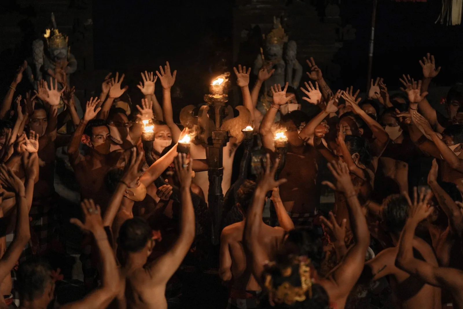 Dancers with raised hands around a fire torch during an evening kecak performance in Ubud