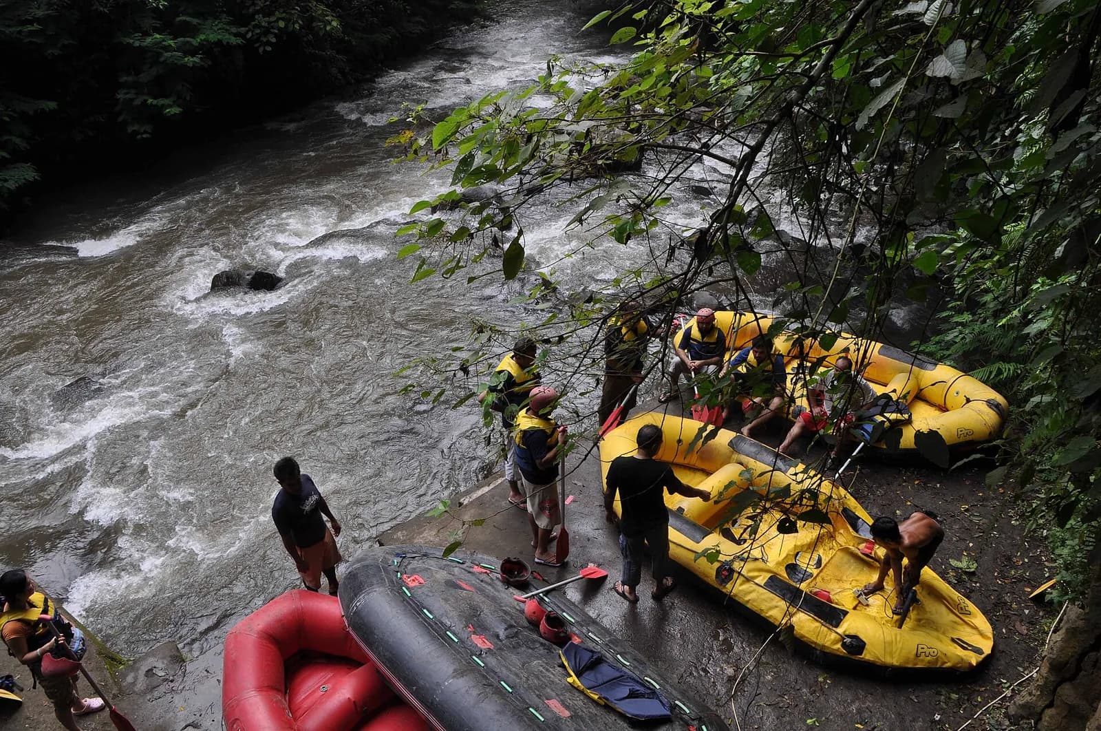 Guides preparing yellow and red rafts on the bank of the Ayung River before a rafting trip near Ubud, Bali