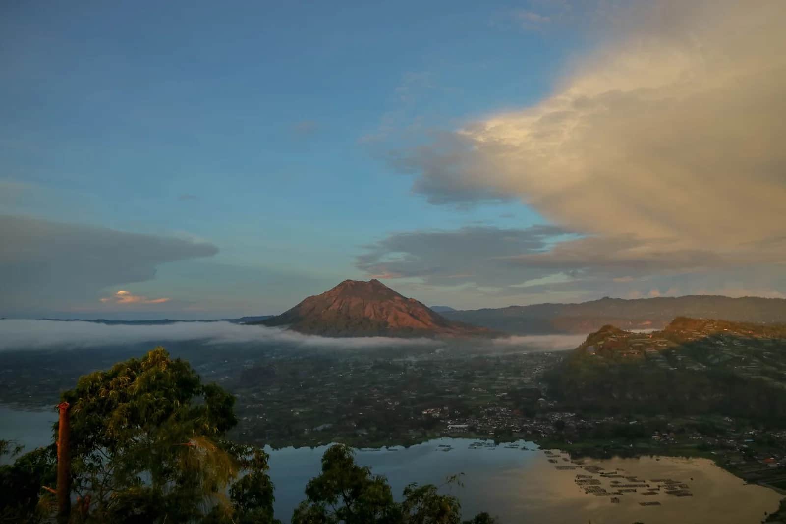 Mount Batur rising above mist and its crater lake at first light, seen from Kintamani