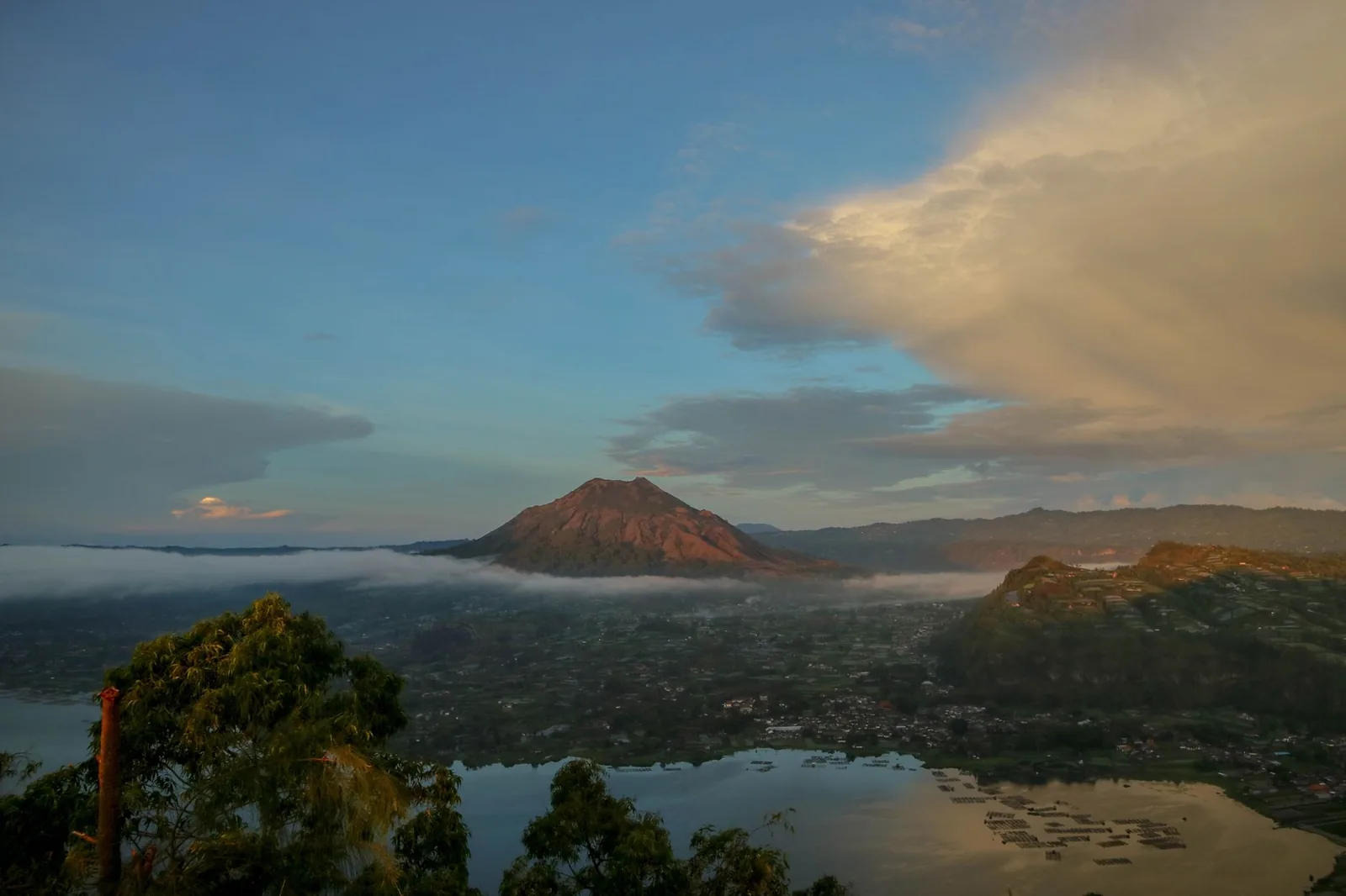 Mount Batur rising above mist and its crater lake at first light, seen from Kintamani