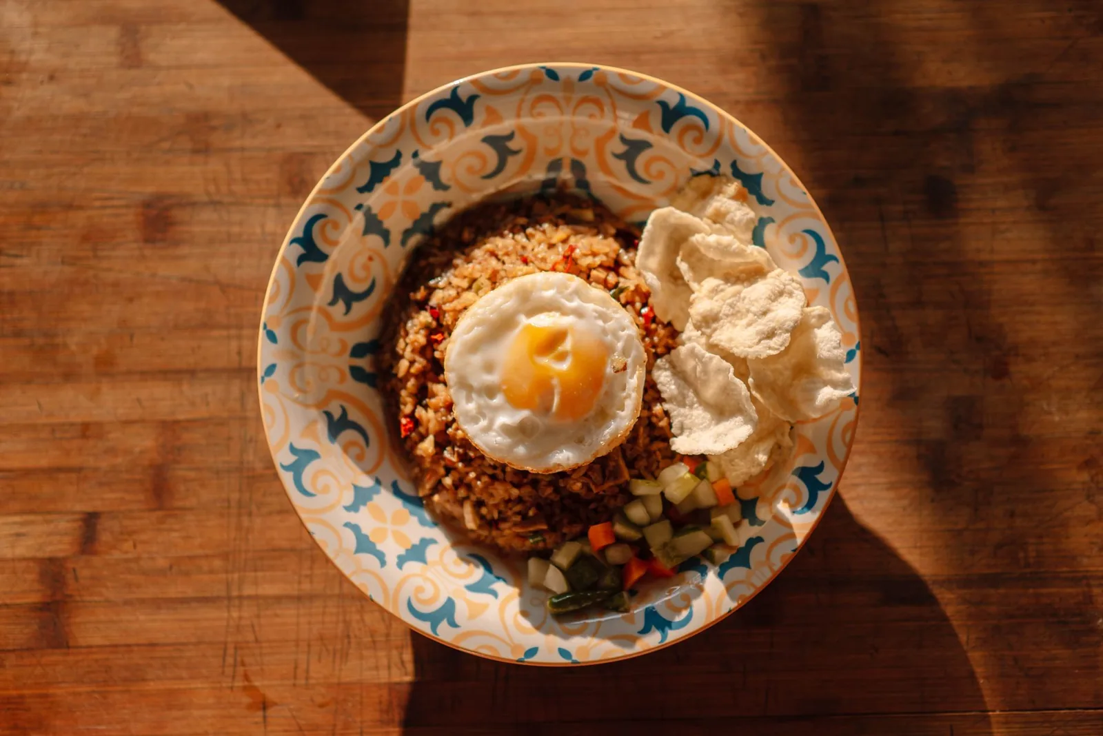 A plate of nasi goreng with a fried egg and prawn crackers on a wooden table in an Ubud warung