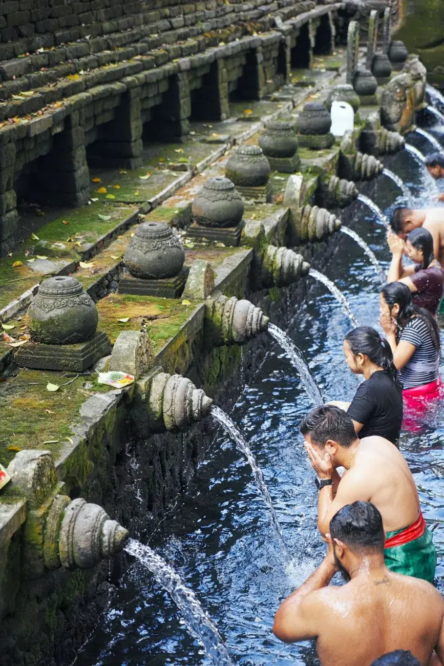 Balinese worshippers praying under the stone spouts in the purification pool at Tirta Empul