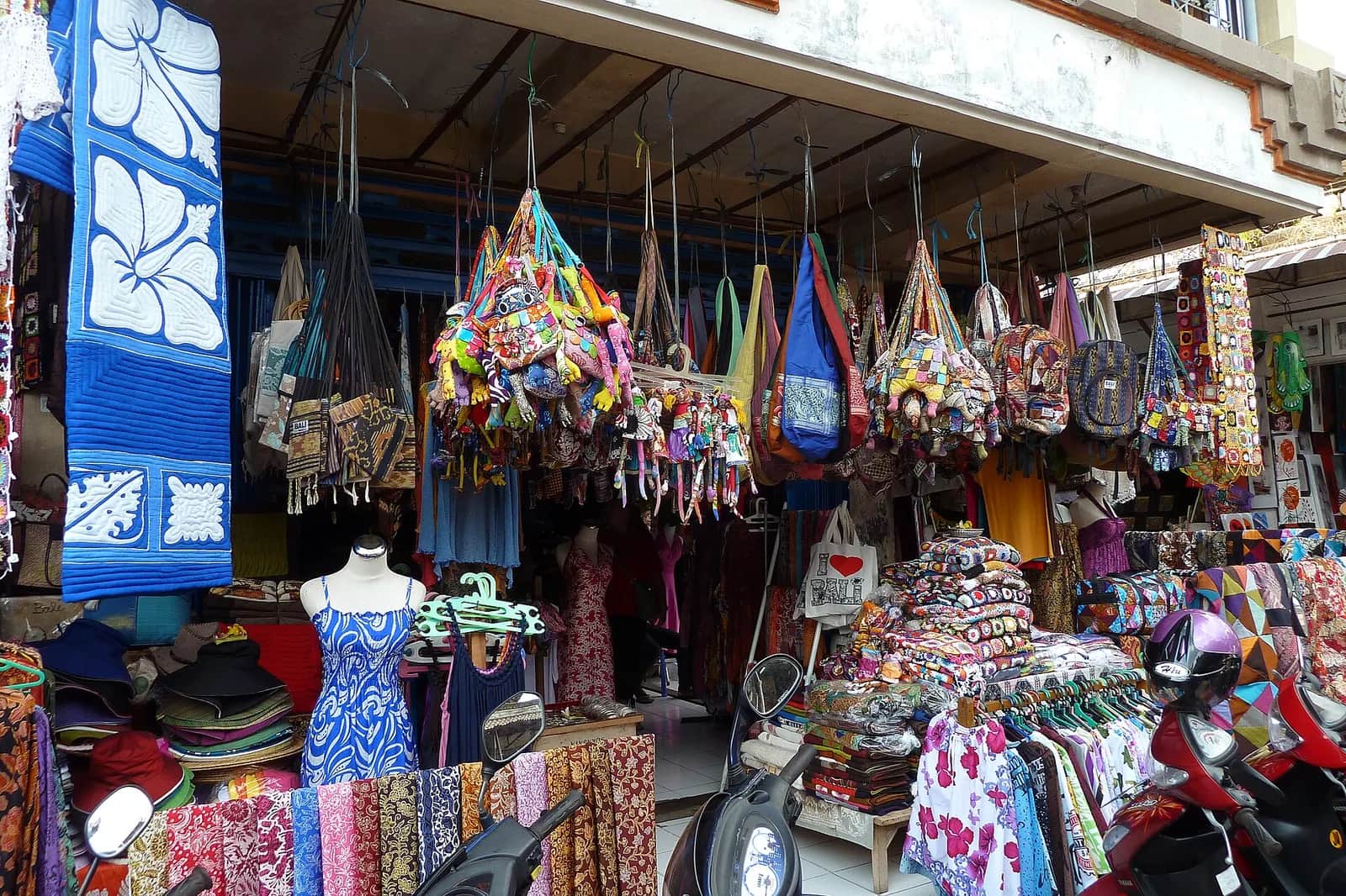Souvenir stall at Ubud Market in Bali with hanging patchwork bags, sarongs and sun hats
