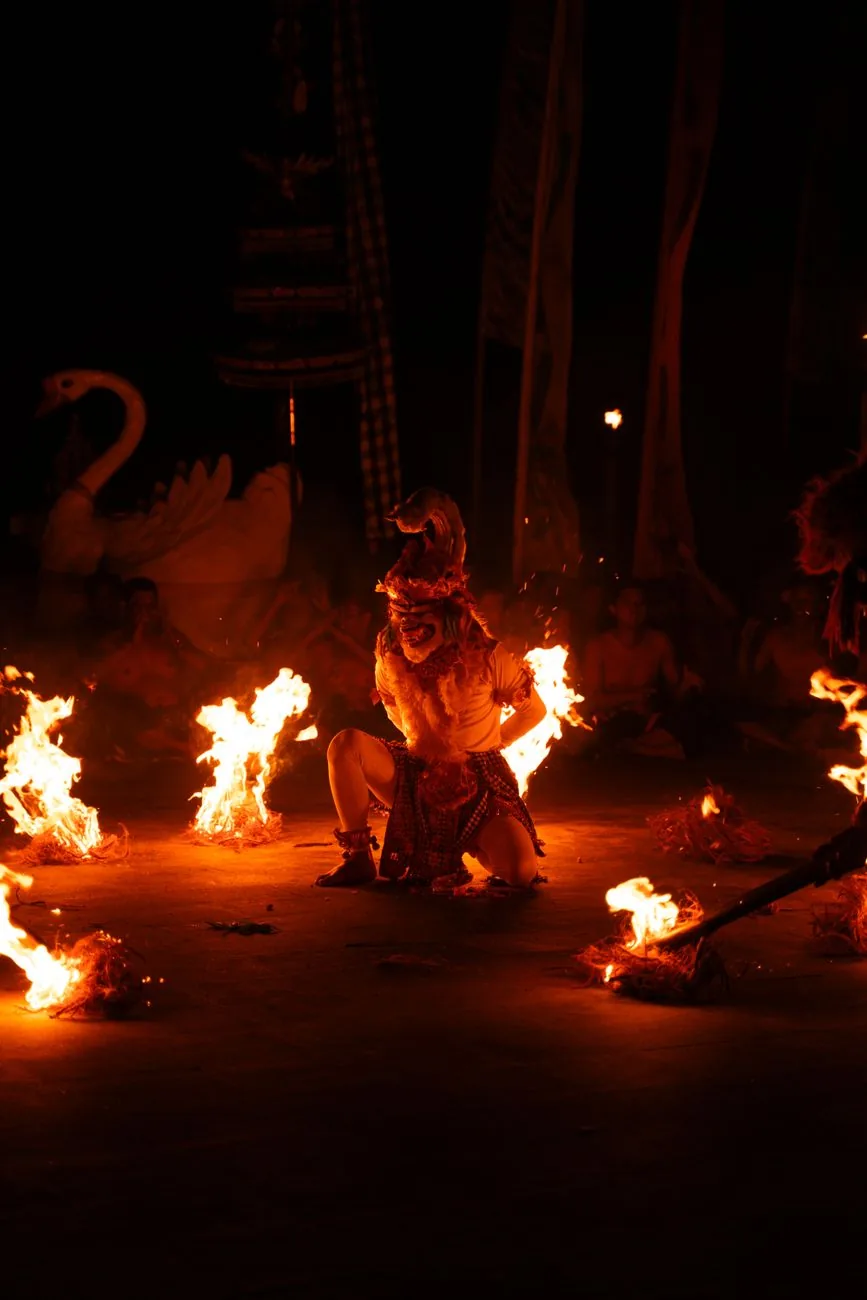 A masked Hanuman performer among burning coconut husks during the fire scene of the kecak at Uluwatu, Bali