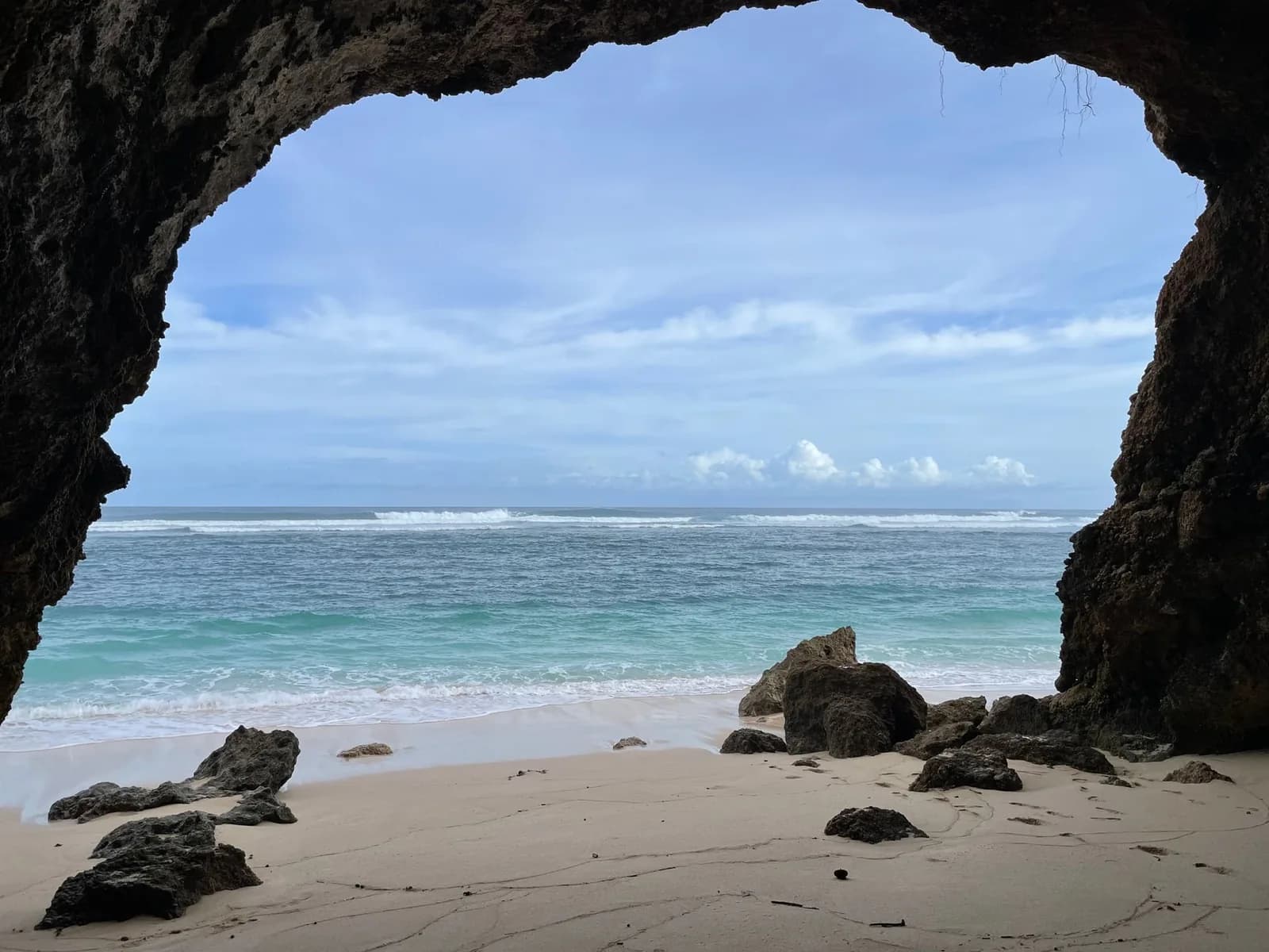 A Bukit peninsula beach in Bali seen through the arch of a sea cave at the foot of the cliff