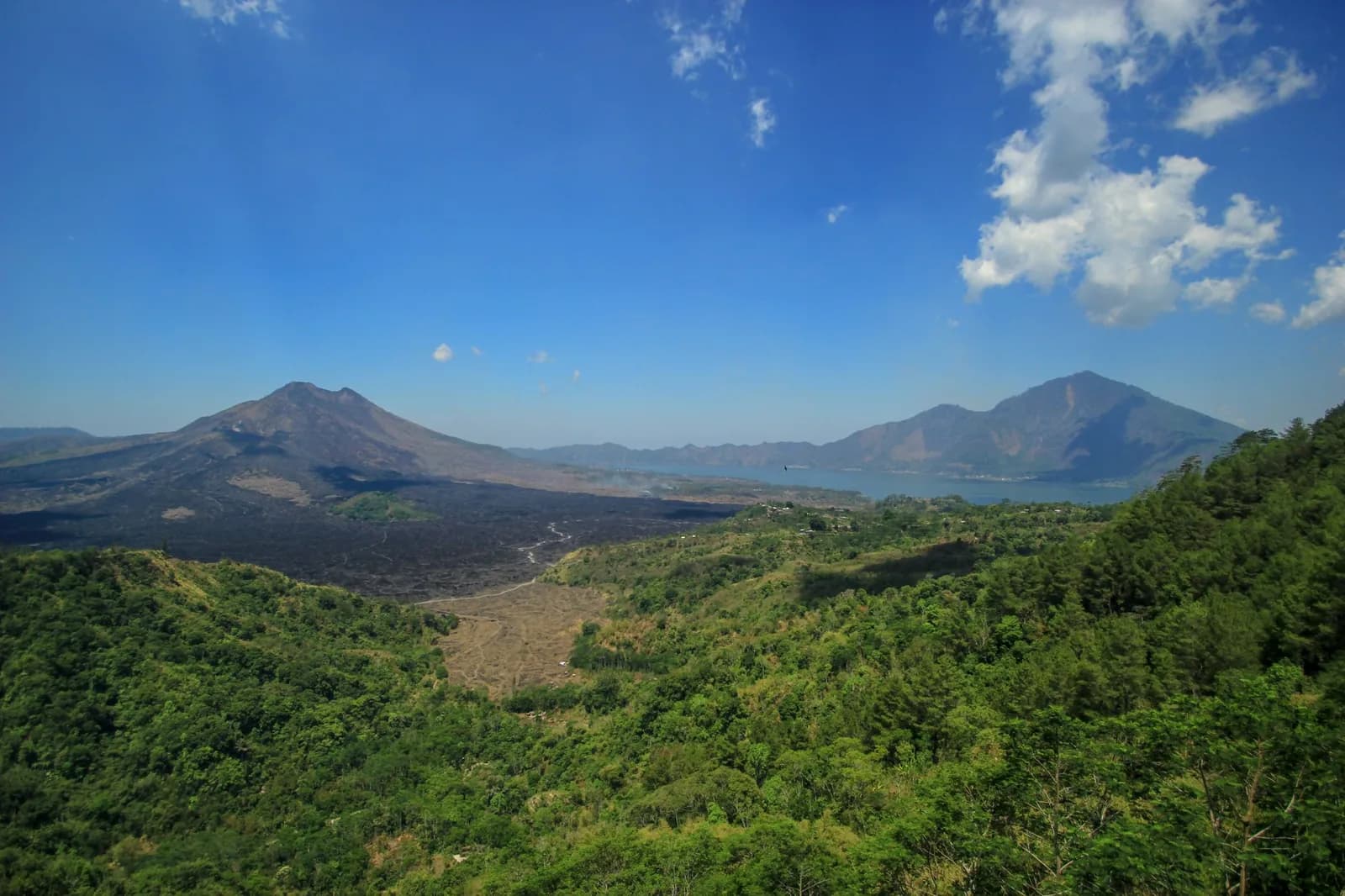 Black lava flows from Mount Batur crossing the caldera floor towards Lake Batur, seen from the Kintamani rim, Bali