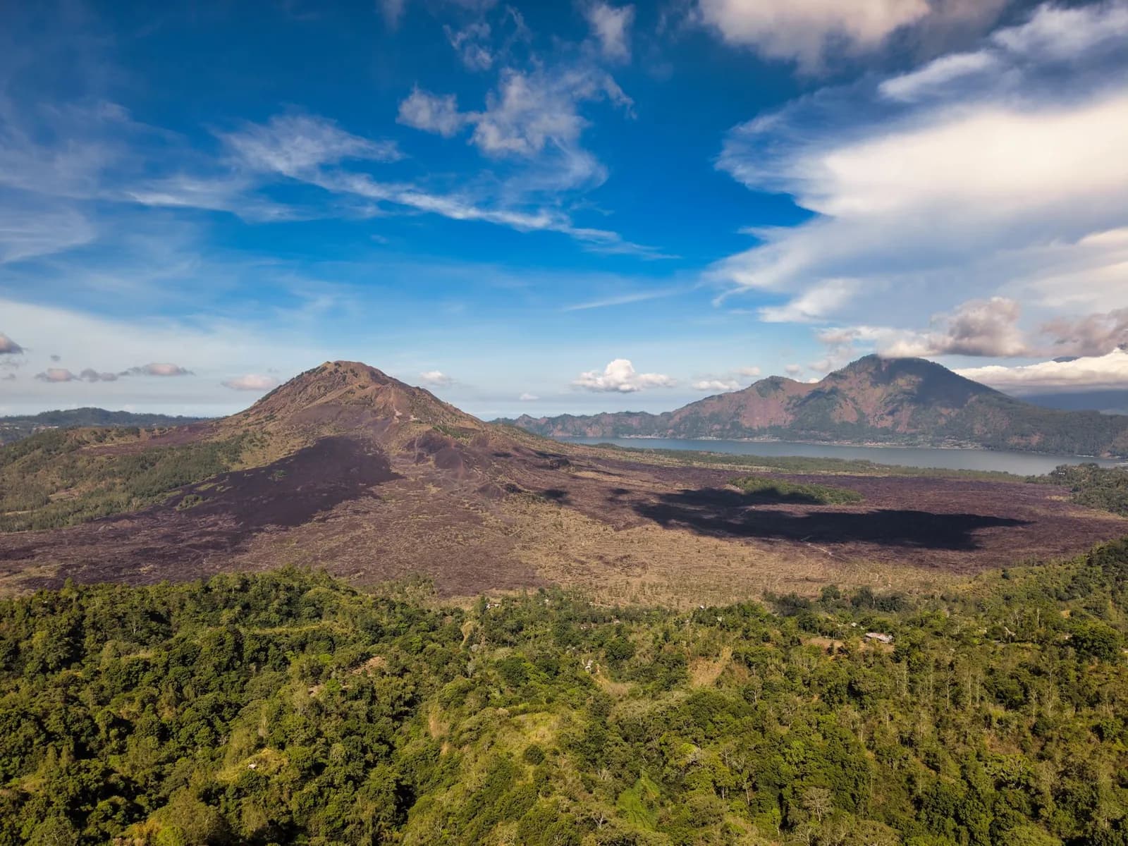 The cone of Mount Batur with its black lava field and Lake Batur behind, seen from the Kintamani rim road, Bali